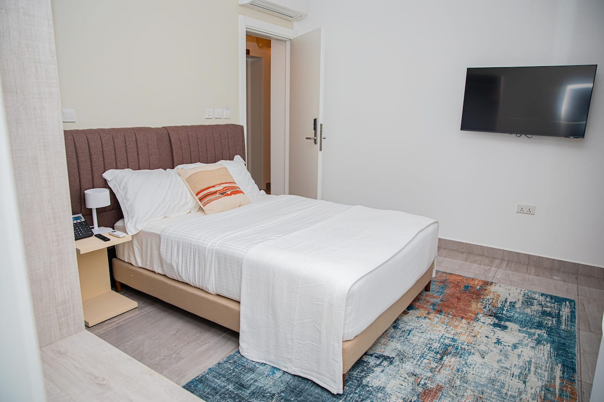 A modern bedroom with a bed, bedside table, and a mounted TV.