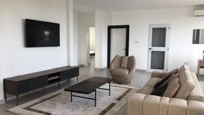 A modern living room with a flat-screen TV, a sofa, a chair, and a coffee table. - CASA BIANCA (Accra)
