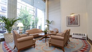 Un vestíbulo con un sofá color beige, dos sillones, una mesa de centro y una alfombra estampada.