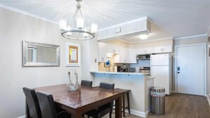 A modern kitchen with white cabinets, a stainless steel refrigerator, and a built-in oven. - Oceanfront Condo w/ Stunning Views and Pool Access (Kill Devil Hills)