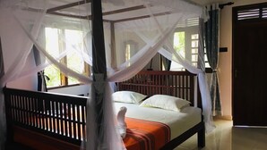Un lit à baldaquin avec des rideaux, une literie blanche et une couverture orange.