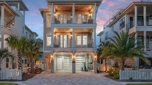 A multi-story residential building with a central entrance, balconies, and a gated driveway. - 4BR New Luxury Build with Huge Private Pool + Sunset Tower Views | Esmeralda (Destin)