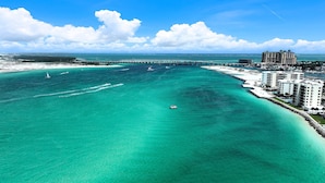 A coastal hotel with a marina, clear turquoise waters, and a bridge in the background. - 4BR New Luxury Build with Huge Private Pool + Sunset Tower Views | Esmeralda (Destin)