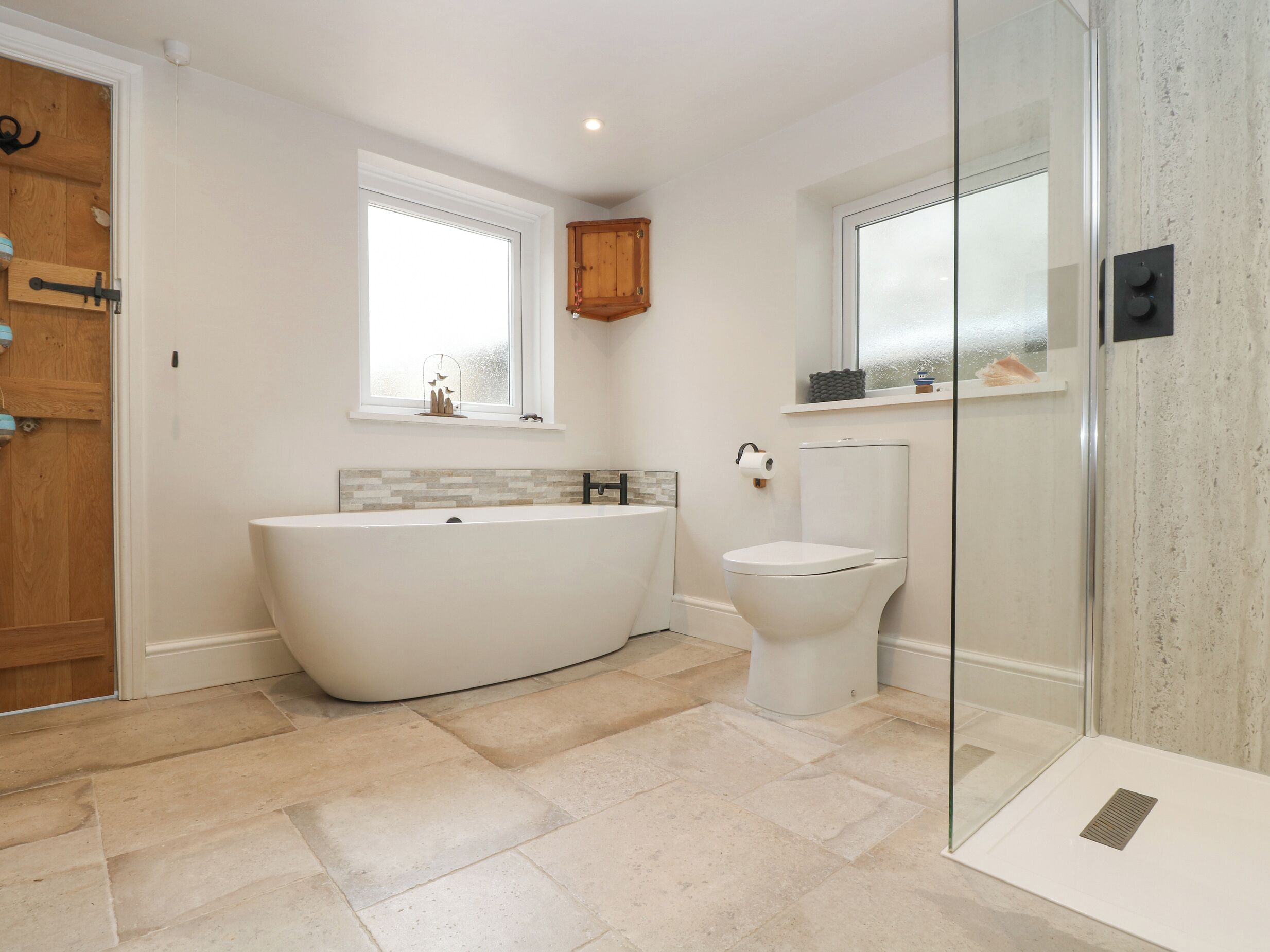 Ein modernes Badezimmer mit freistehender Badewanne, Toilette und einer Duschkabine aus Glas.