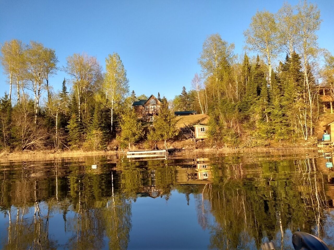 A lakeside property with a cabin, dock, and surrounding forest.