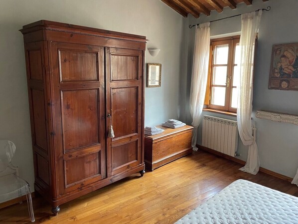 A room with a wooden wardrobe, a small chest of drawers, a window with curtains, and a bed. - Exclusive retreat in the historic center of Lucca, overlooking Piazza Anfiteatro (Lucca)