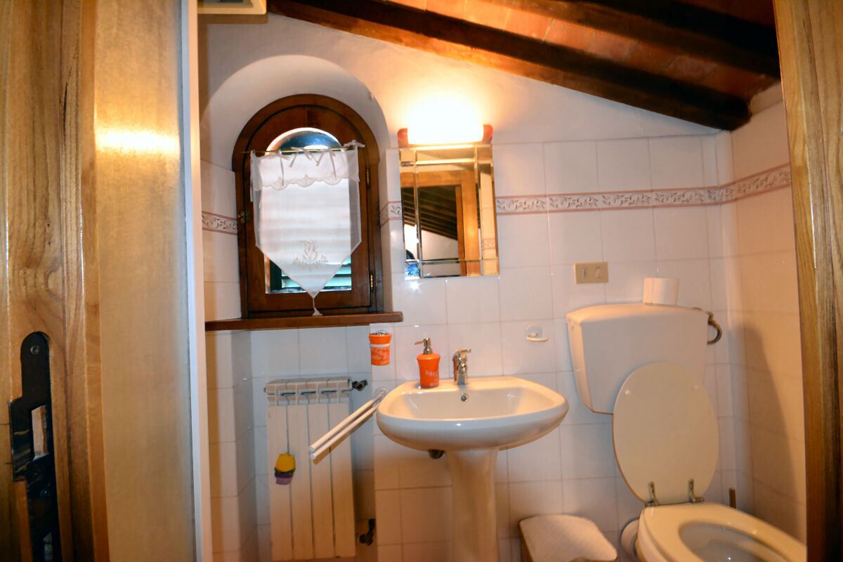 A bathroom with a white sink, toilet, and a window with a curtain.