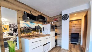 Eine moderne Küche mit weißen Schränken, einer Holz Arbeitsplatte und einer eingebauten Mikrowelle. Eine dekorative Wanduhr und ein Kamin sind ebenfalls vorhanden.