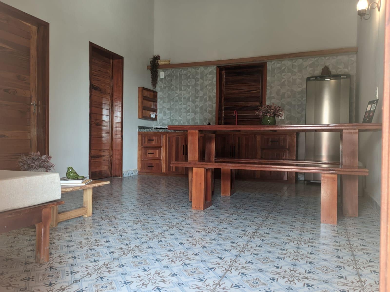 Une cuisine compacte avec des meubles en bois, un banc intégré et un réfrigérateur.