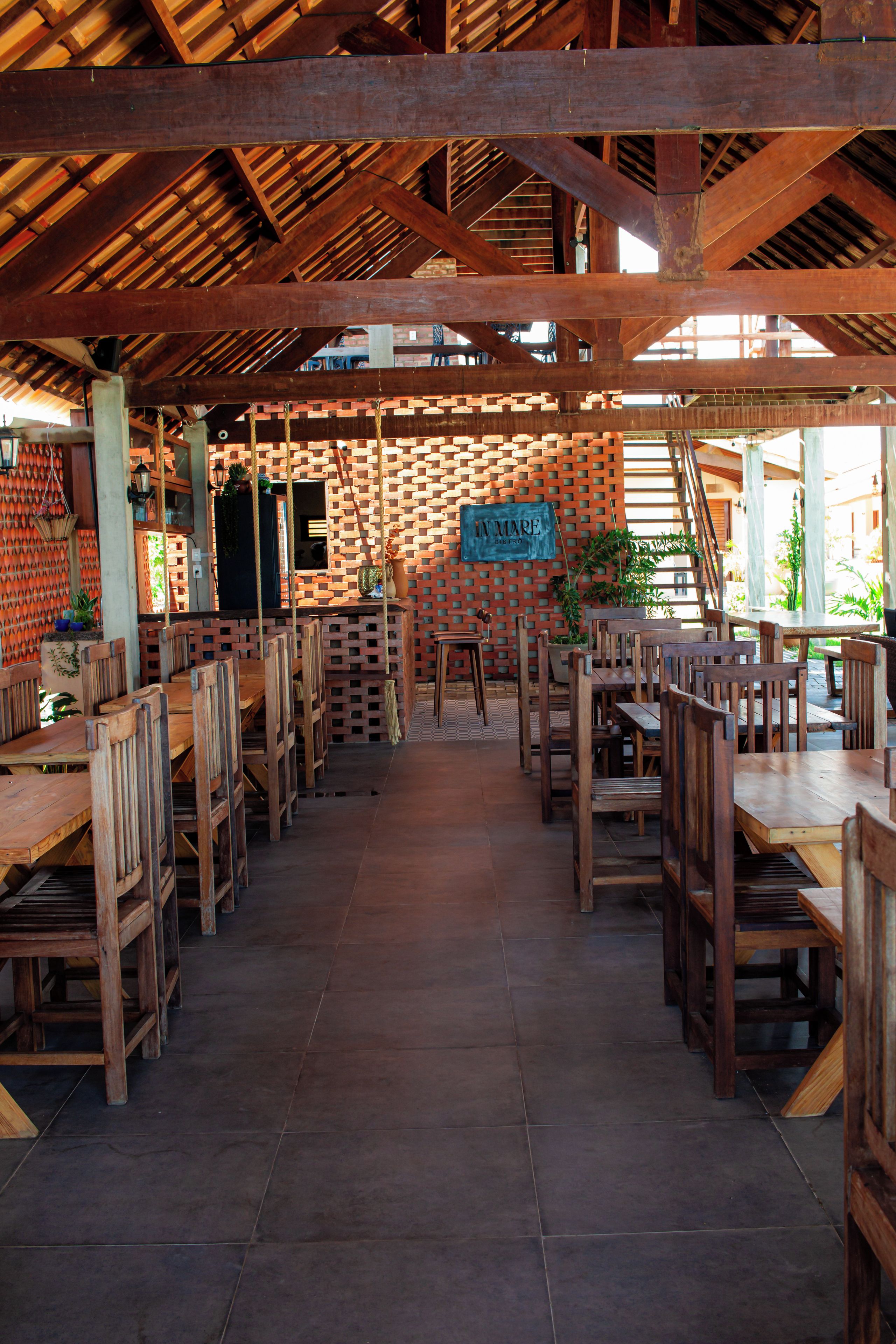 A restaurant with a brick wall, wooden tables and chairs, and a sign reading 'IN MARE BISTRO'.