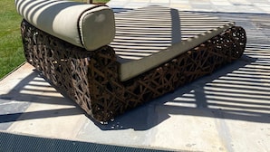 Un área de descanso junto a la piscina, con vista al océano, una estructura de techo de paja y un deck con baldosas de piedra.