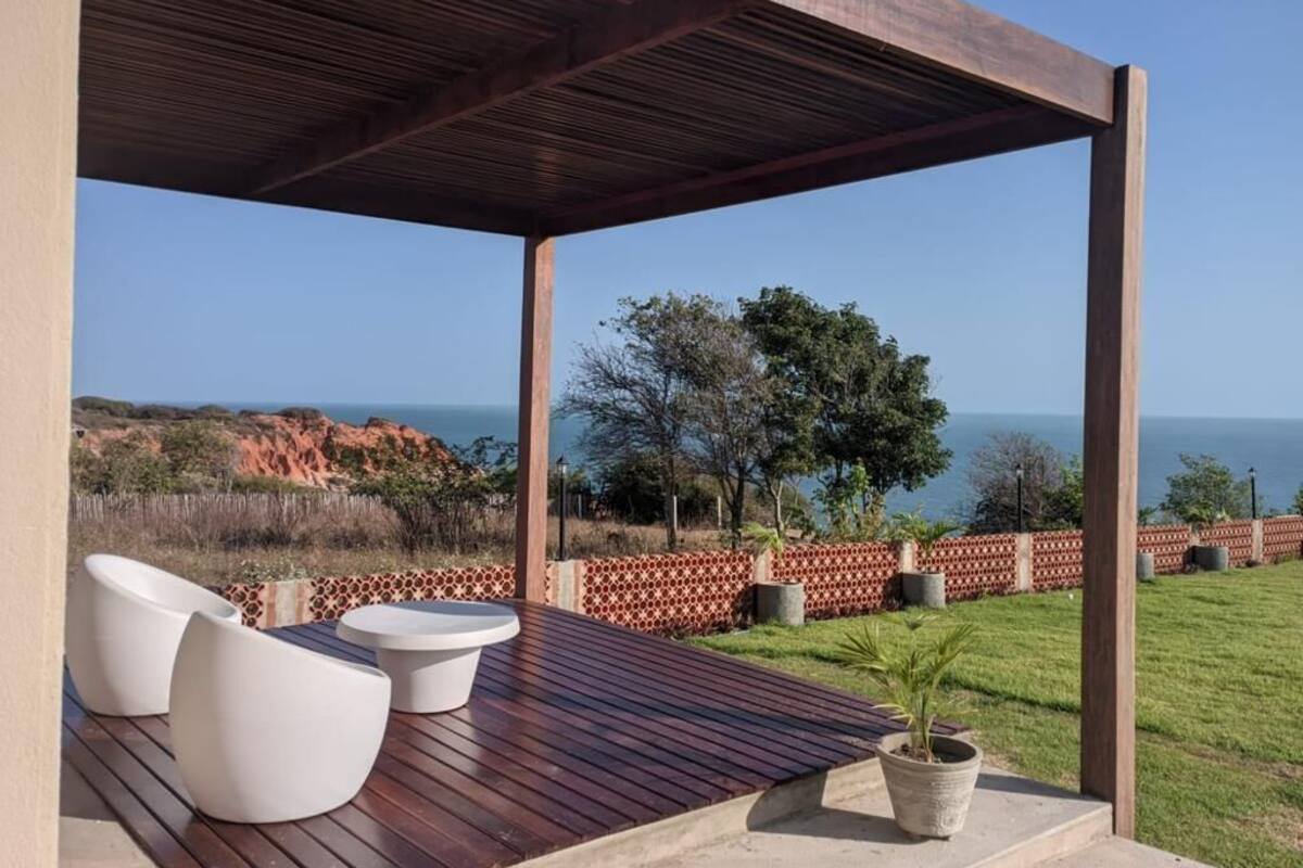 An outdoor patio with wooden flooring, white chairs, and a potted plant.