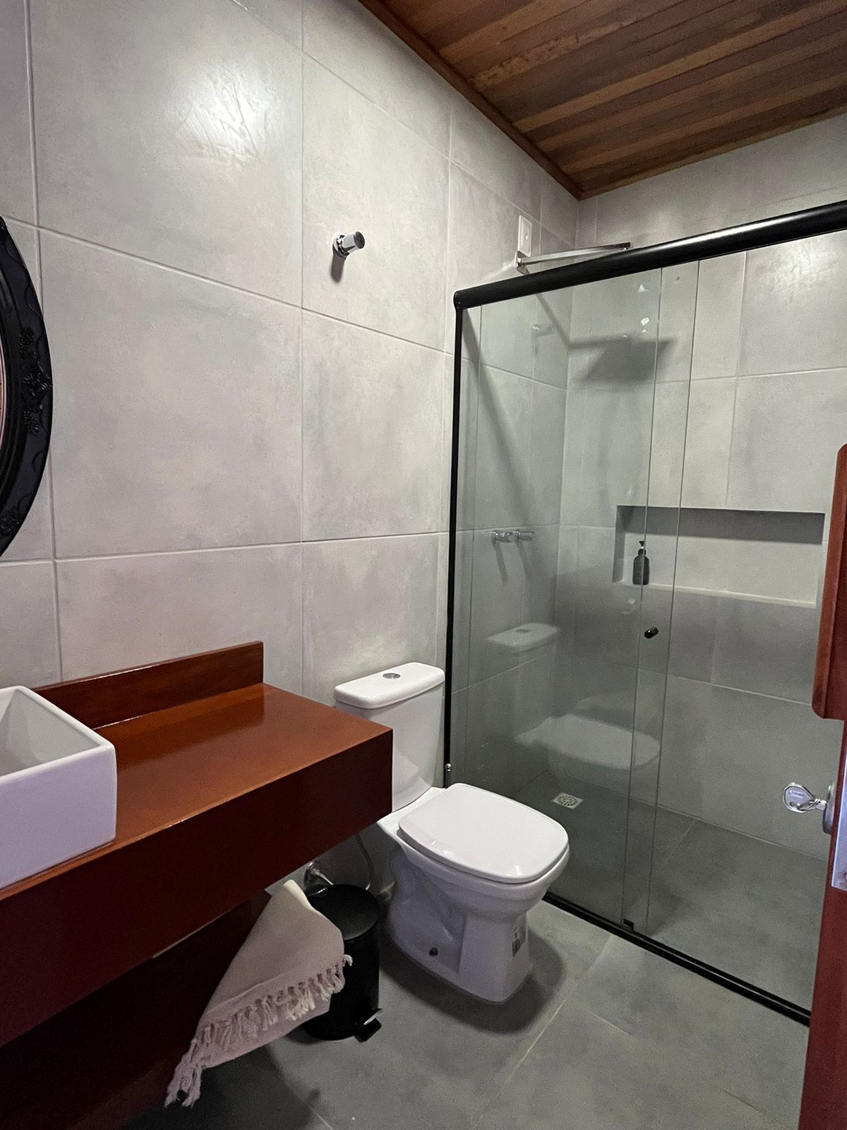 A modern bathroom with a glass shower enclosure, a wooden vanity, and a white toilet.