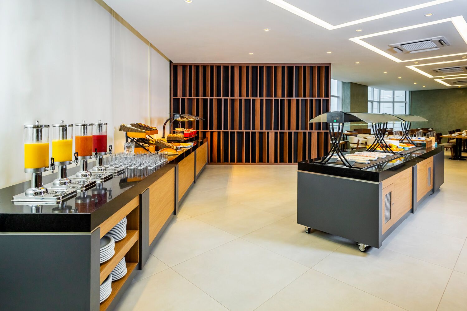 A buffet area with juice dispensers, a variety of food options, and a seating area with tables and chairs.