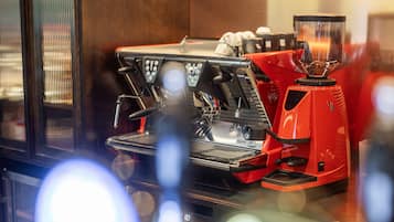 Una máquina de espresso roja con pantalla digital, espumador de leche y molinillo.
