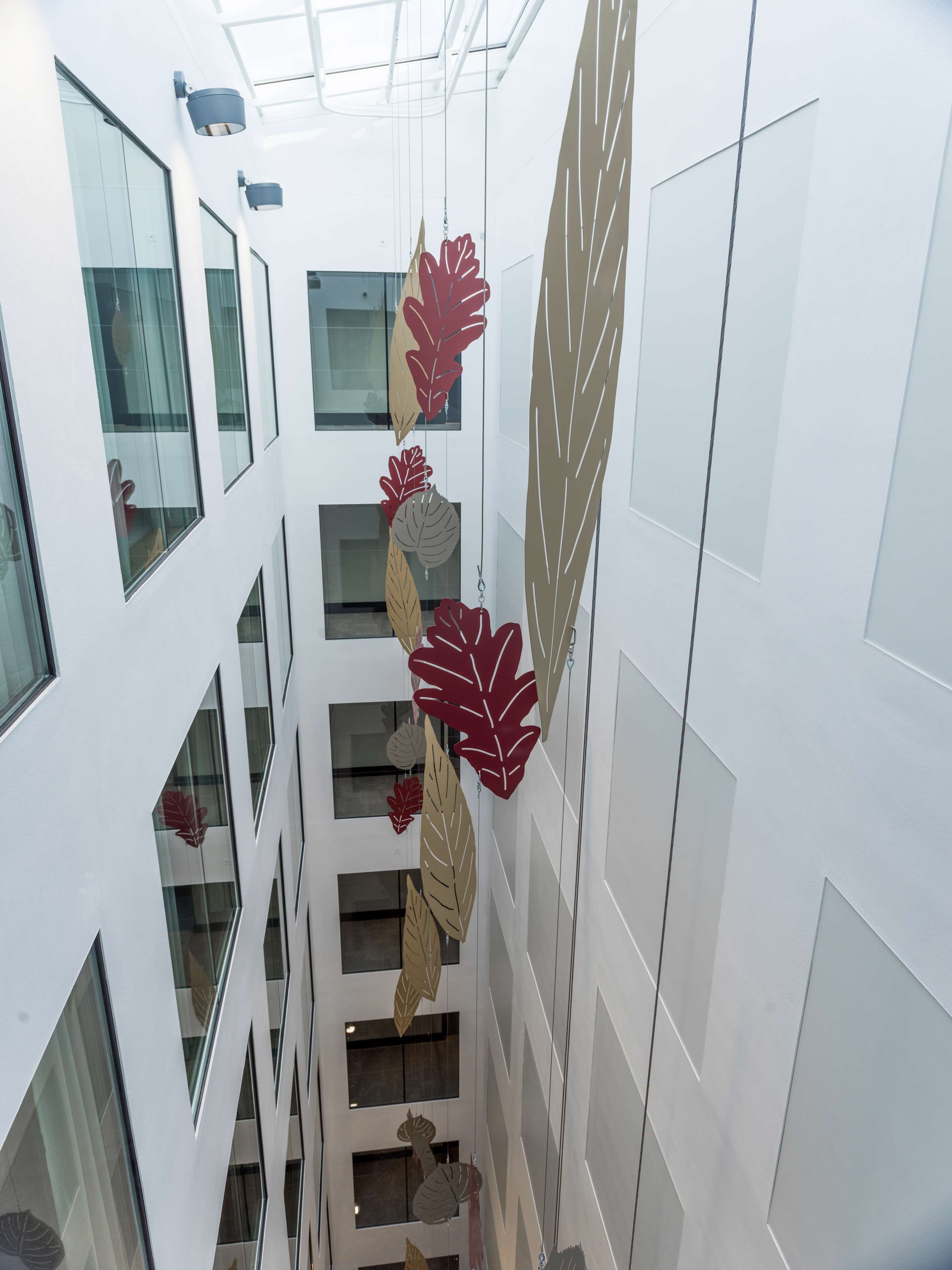 A modern interior with a central staircase flanked by glass walls and decorative leaf motifs.