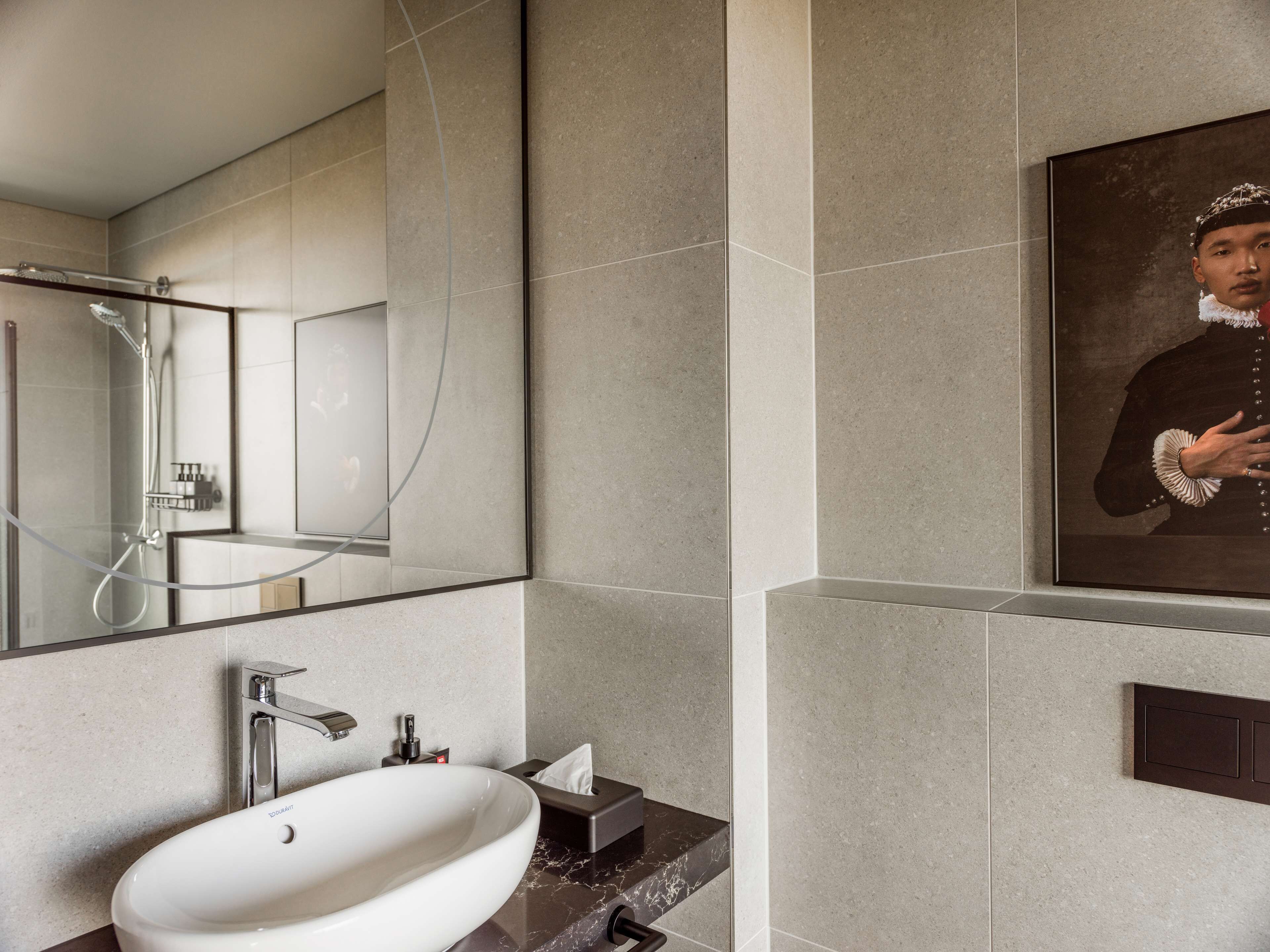 Une salle de bain moderne avec un grand miroir, un lavabo et une douche.