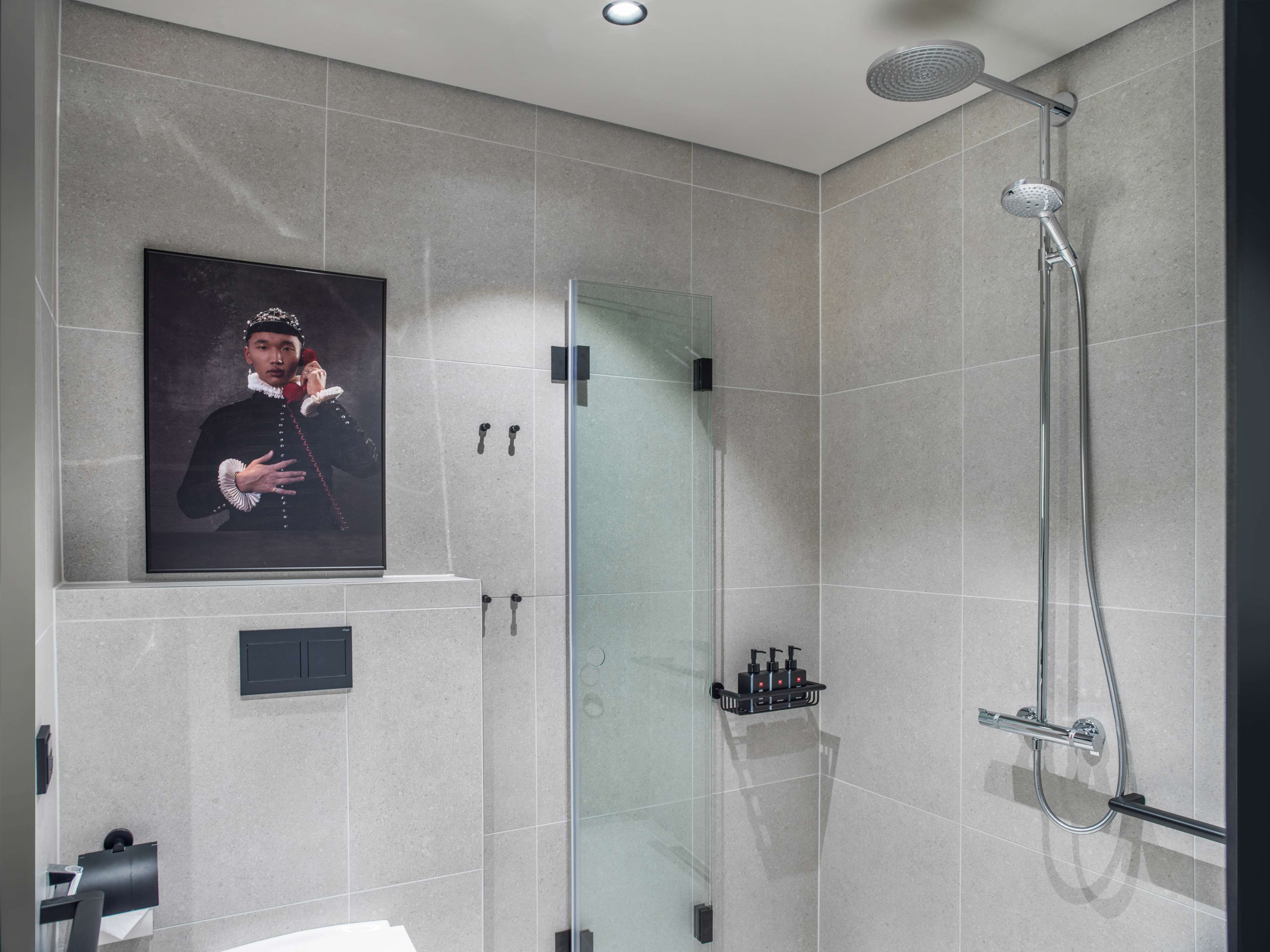 A modern bathroom with a glass shower enclosure, a mounted picture, and a towel rack.