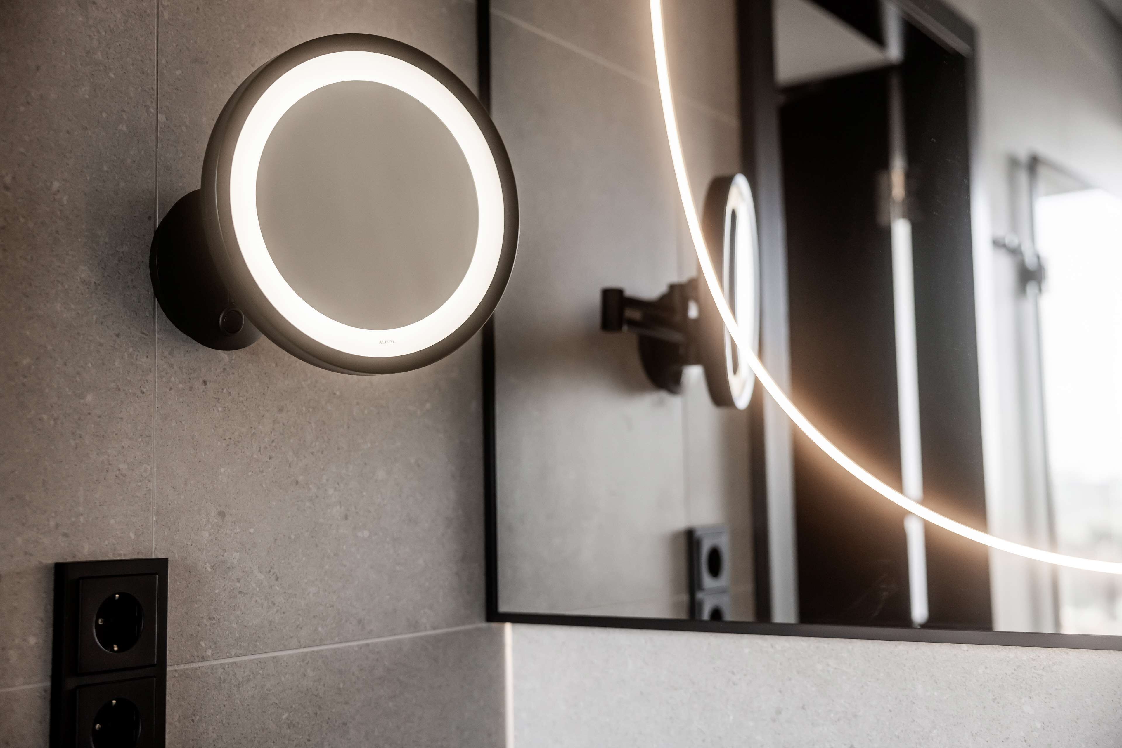 A bathroom with a wall-mounted mirror and a circular light fixture.