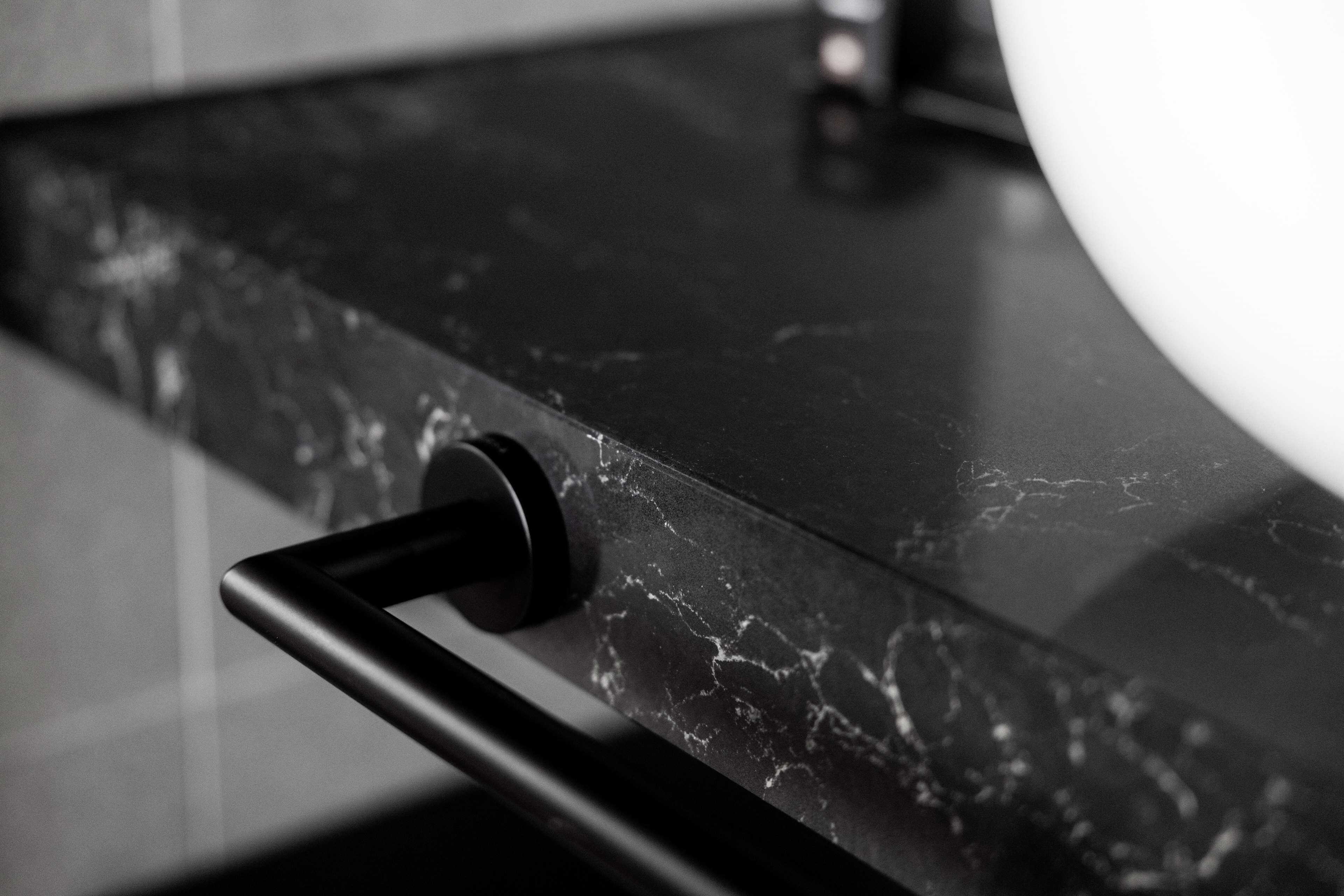 A close-up of a black marble countertop with a faucet and a black handle.
