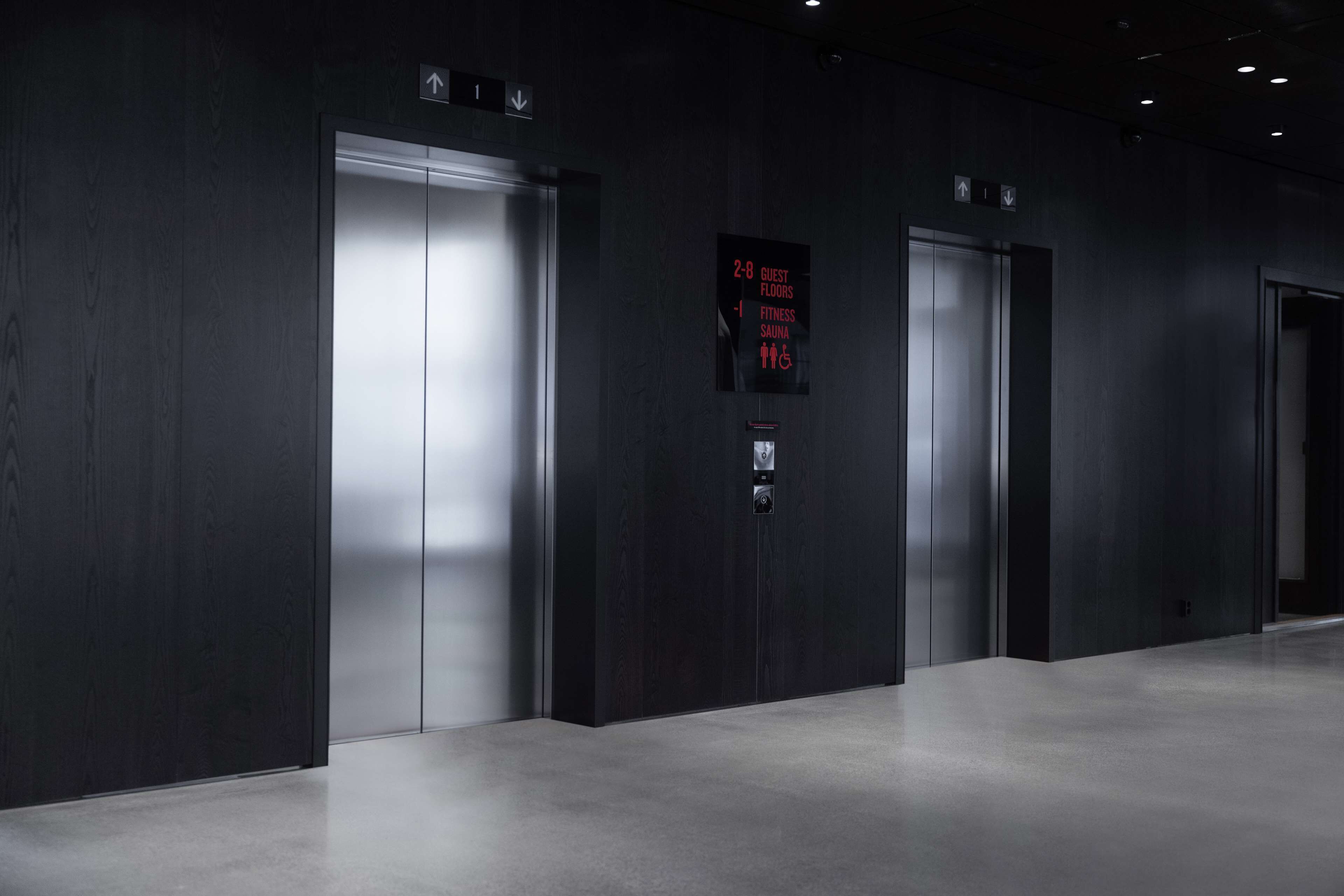 Ein moderner Aufzug mit digitaler Anzeige, die die Etagen 2 bis 8 für Gäste, Fitnessbereich und Sauna anzeigt.