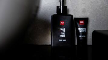 A black bottle of hand wash and a tube of body lotion with a pump dispenser, both labeled 'RED'.