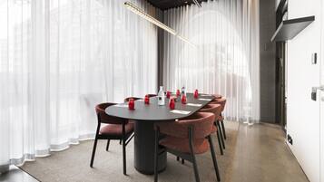 A modern conference room with a round table, red upholstered chairs, and a pendant light.