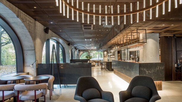 Un interior moderno con luces de techo curvas, una zona de bar y diferentes disposiciones de asientos.