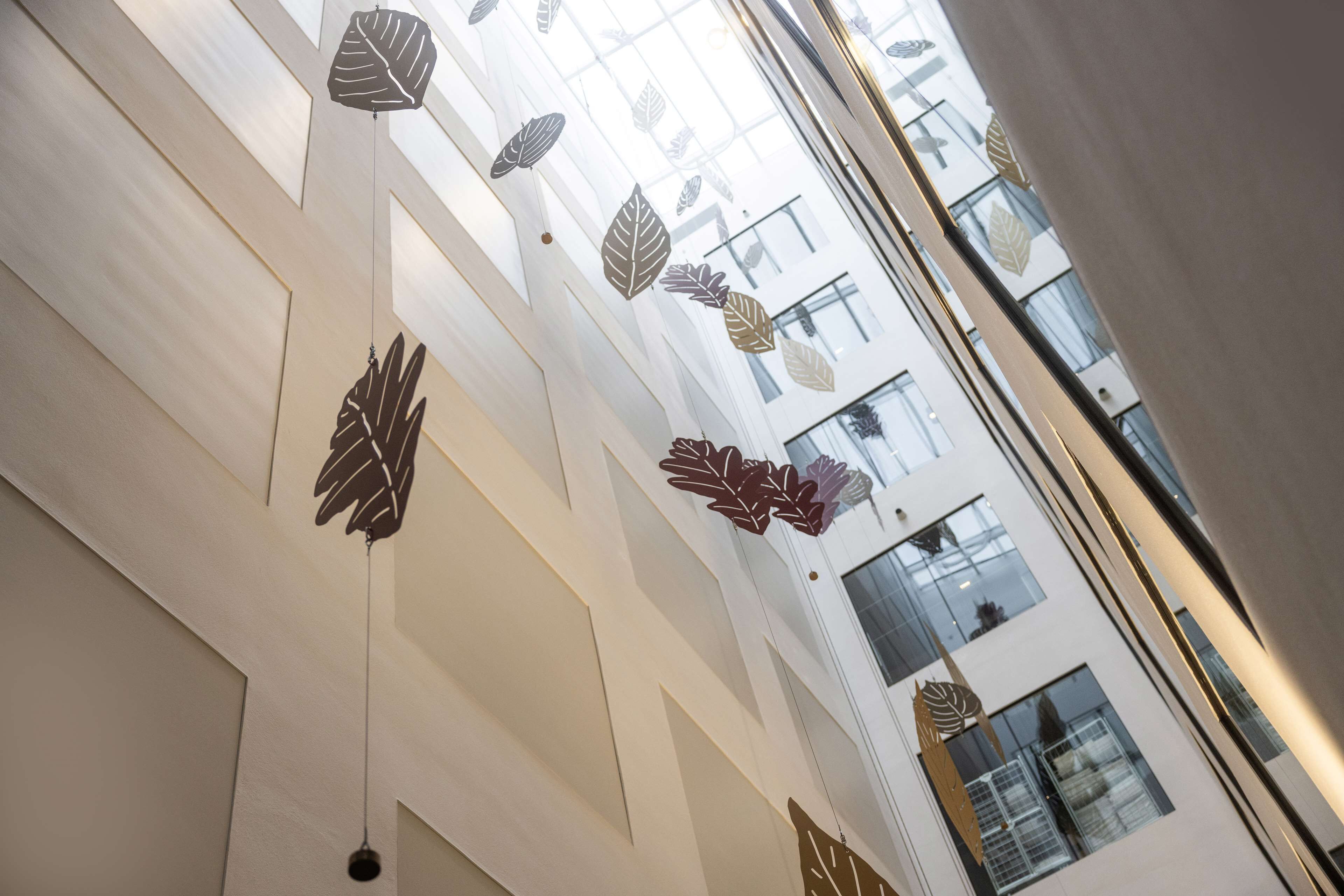 Un interior moderno con diseños geométricos en la pared y decoraciones con hojas colgantes.