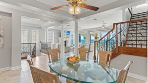 A spacious dining area with a glass-top table surrounded by wooden chairs, a ceiling fan, and a view of the living area. - Hot Tub - Destiny by the Sea Gated Community- 5-Star Reviews - On the Beach (Destin)