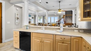 A spacious kitchen with a dishwasher, wooden cabinets, and a large island. - Hot Tub - Destiny by the Sea Gated Community- 5-Star Reviews - On the Beach (Destin)