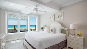 A bedroom with a large bed, a nightstand, a dresser, and a view of the beach. - Hot Tub - Destiny by the Sea Gated Community- 5-Star Reviews - On the Beach (Destin)