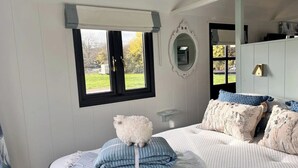 Un dormitorio con cama, ventana, espejo y armario.