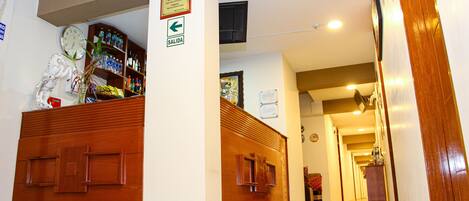 A hotel lobby with a reception desk, a clock, and a sign indicating the exit.