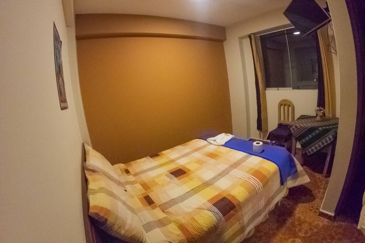 Une petite chambre confortable avec un lit simple, une fenêtre et une petite table avec une chaise.