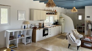 A modern kitchen with white cabinets, a wooden countertop, and hanging light fixtures. - Cosy open plan studio for couples or singles (Alyki)