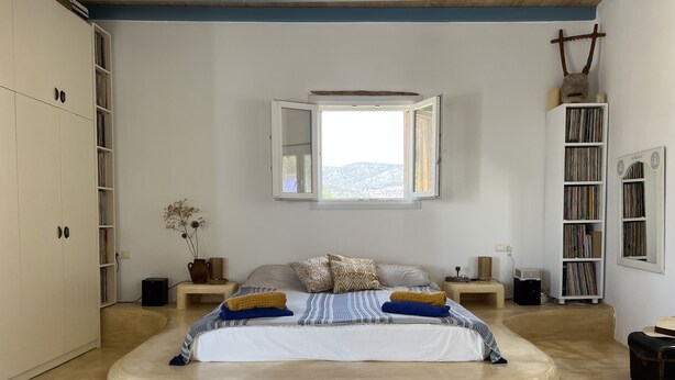 A bedroom with a large bed, a window with an open view, a bookshelf, and a wardrobe. - Cosy open plan studio for couples or singles (Alyki)