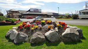 A hotel named 'LYONS' with a garden in front featuring colorful flowers and large rocks. - Sleeps 6, Gym, Entertainment, Pool, Beach (Rhyl)