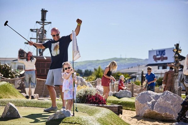 A golf course with a flagstick, a sign for 'Lions', and people playing. - Sleeps 6, Gym, Entertainment, Pool, Beach (Rhyl)