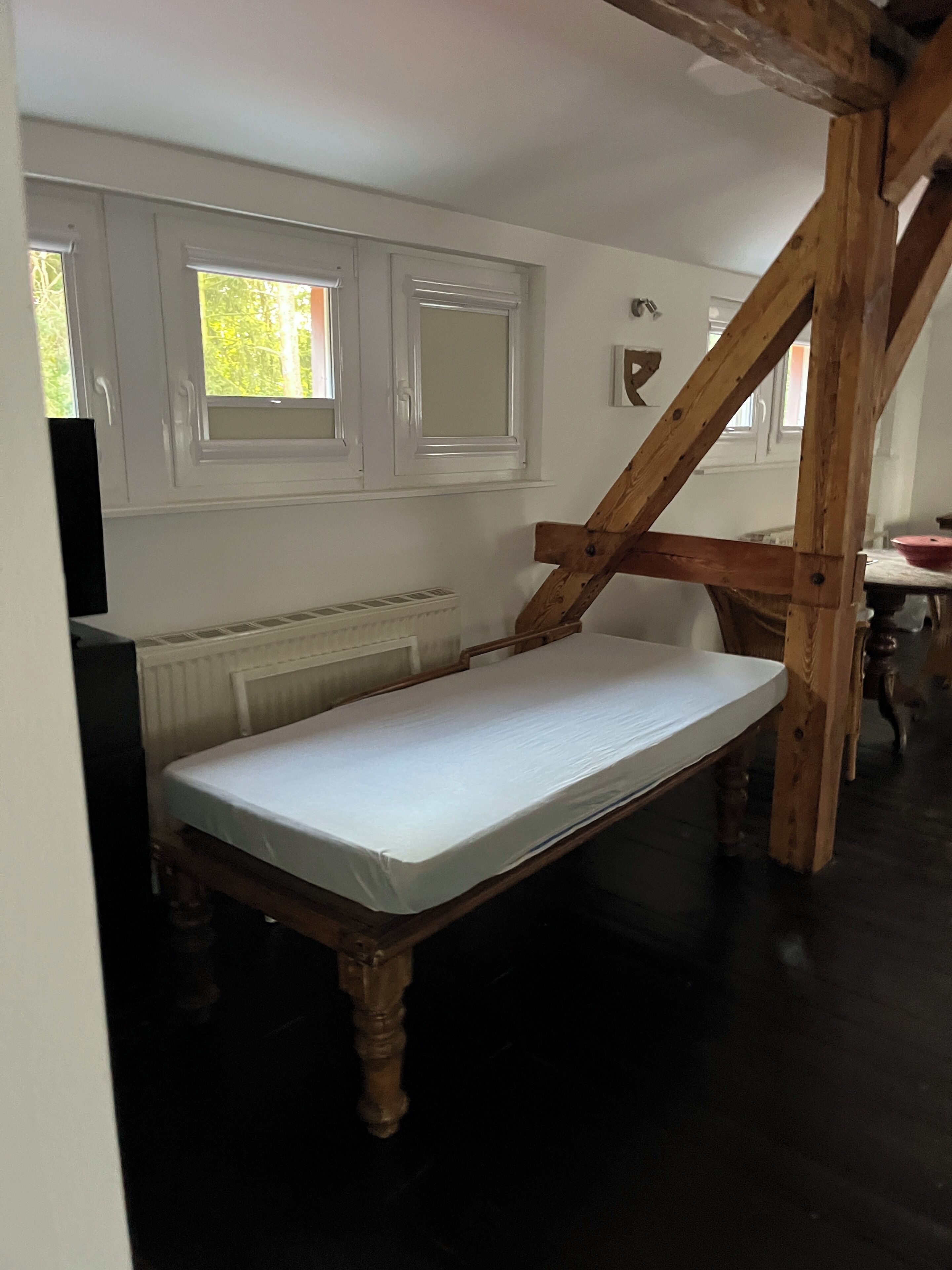 A room with a wooden bed, white walls, and a window.