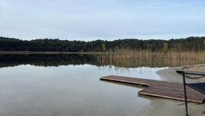 A calm lake with a wooden dock extending into the water, surrounded by dense forest. - Park Residenz Bei Wu (Wesenberg)