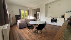 A modern living space with a round dining table, black chairs, a grey sofa, and a kitchen area. - Park Residenz Bei Wu (Wesenberg)