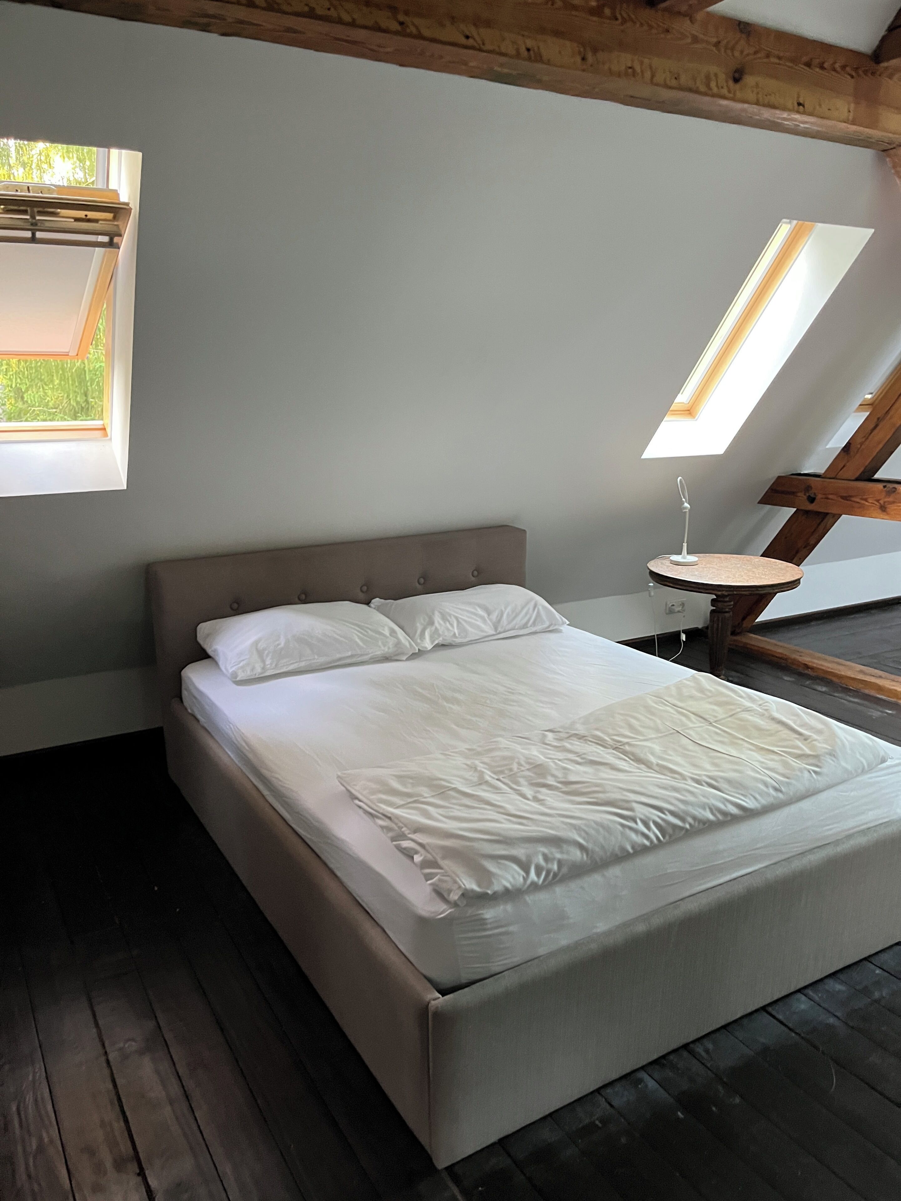 Une chambre à coucher avec un lit, une lucarne et une petite table.