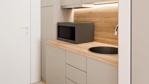 A modern kitchen with a built-in microwave, a sink, and wooden cabinetry. - Plagia Relax Hotel (Nea Propontida)