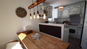 A kitchen with a wooden island, pendant lights, and white cabinetry.
