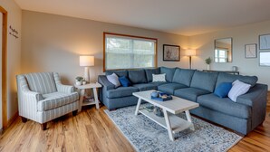 A living room with a striped armchair, a grey sectional sofa, a white coffee table, and a blue rug. - Spacious Hammondsport Home on 6 Acres w/ Lake View (Hammondsport)