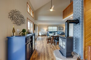 Una sala de estar moderna con chimenea, un comedor y una cocina con una isla azul.