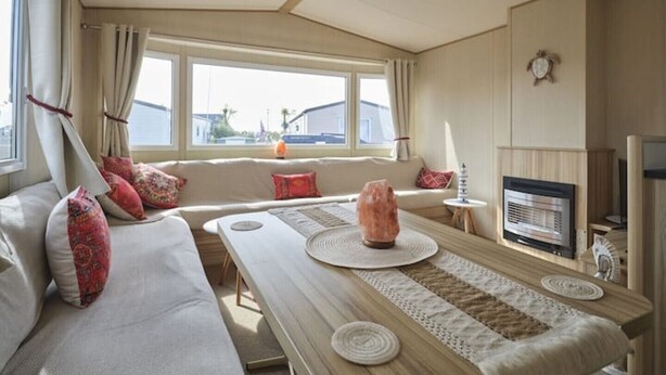 Ein gemütliches Zimmer mit einer Couch, einem Tisch, einem Kamin und einem Fernseher.