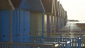 Eine Reihe von Holzhäusern am Meer mit Balkonen, wahrscheinlich Strandhäuser, entlang einer Küstenpromenade.
