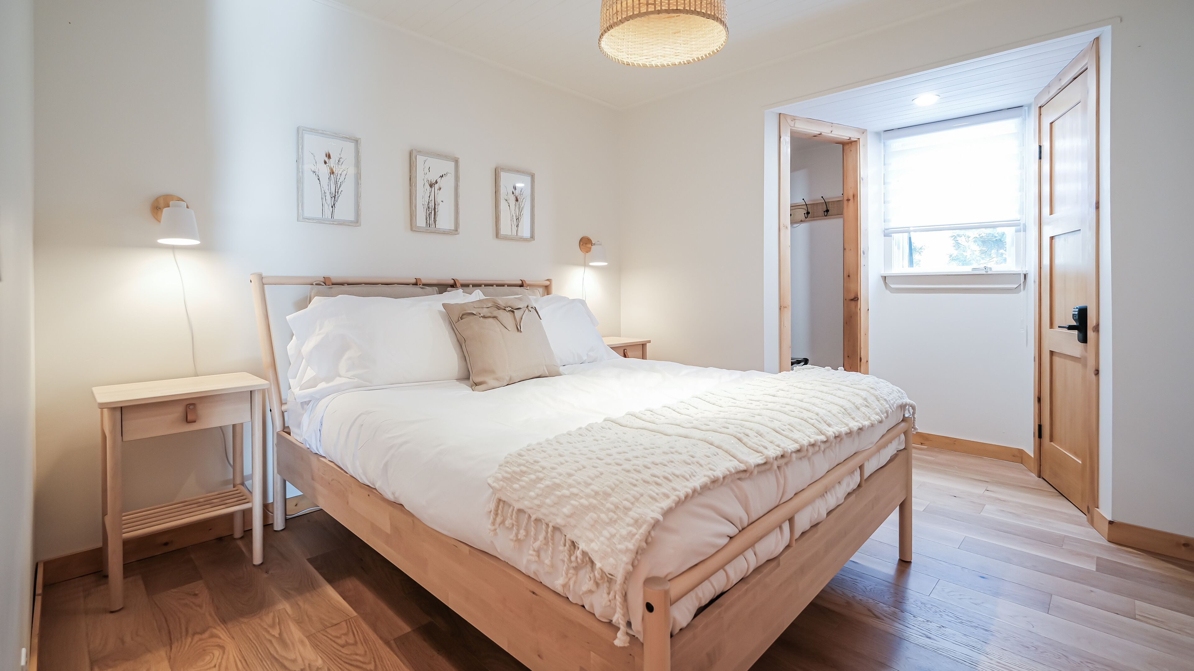 Un dormitorio con una cama de madera, mesitas de noche y luces fijadas a la pared.